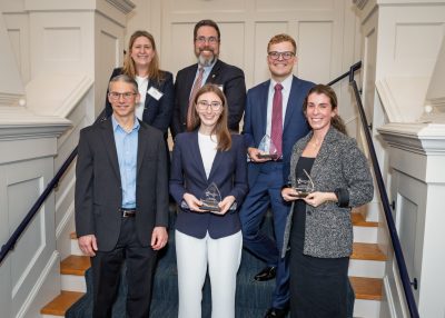 Six people pose together on a staircase at a UConn College of Engineering event, with three award recipients holding GOLD Rising Star trophies.